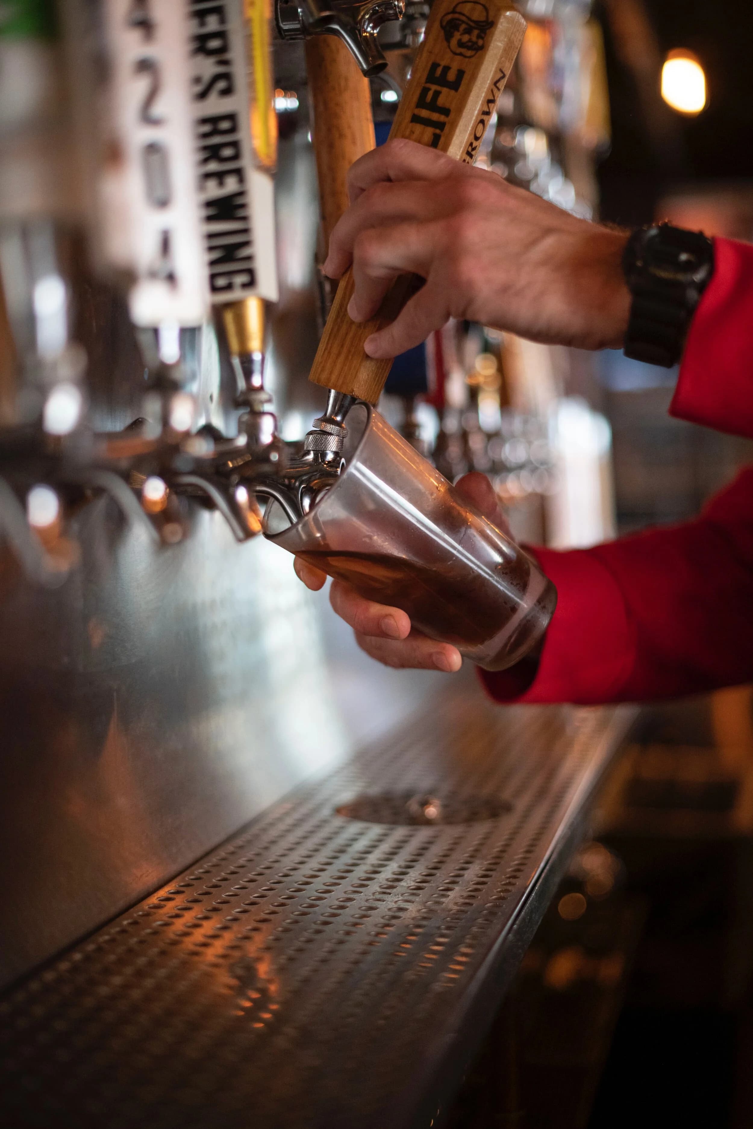 A bartender's hands pouring a pint from the draft wall