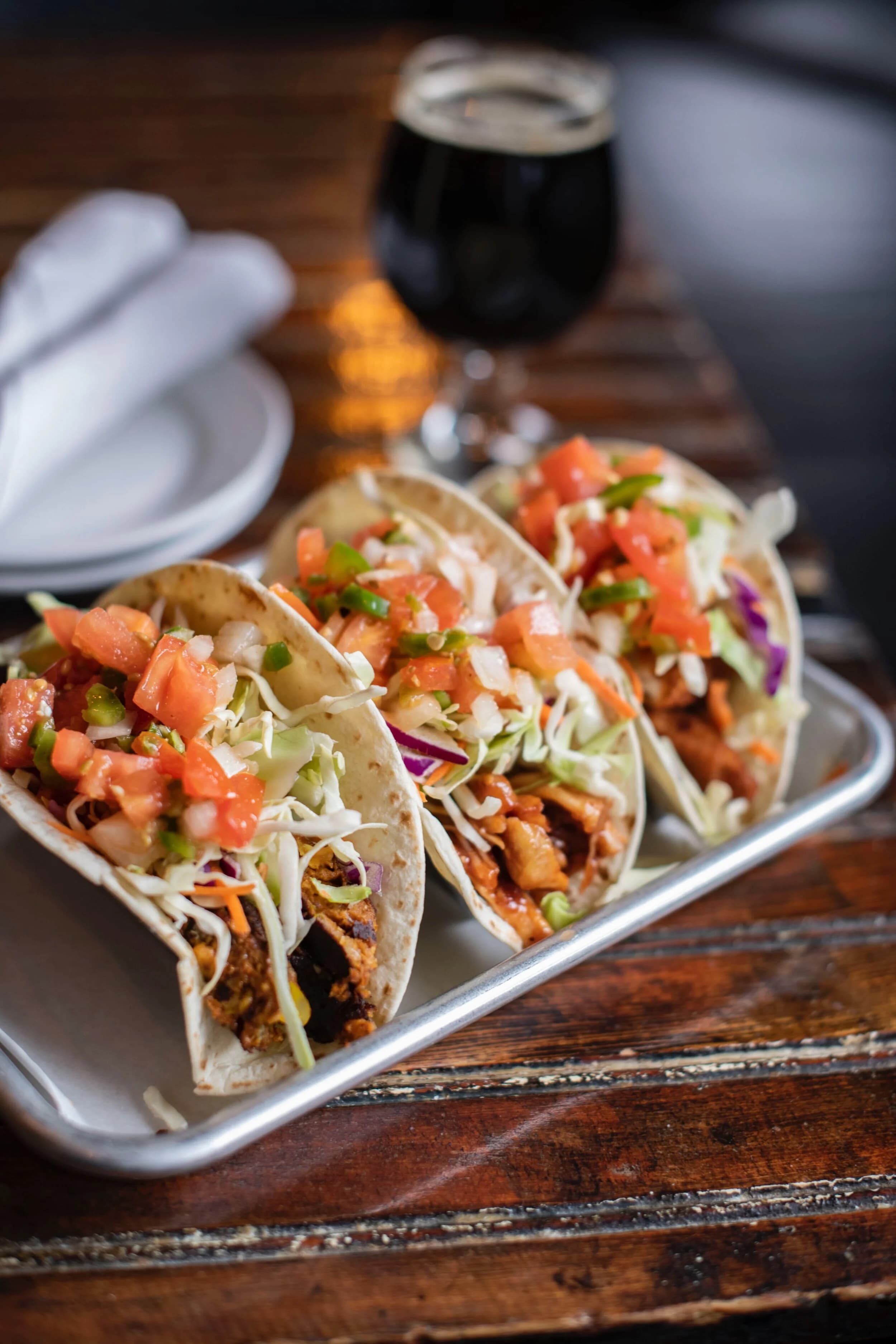 Three plated tacos with toppings