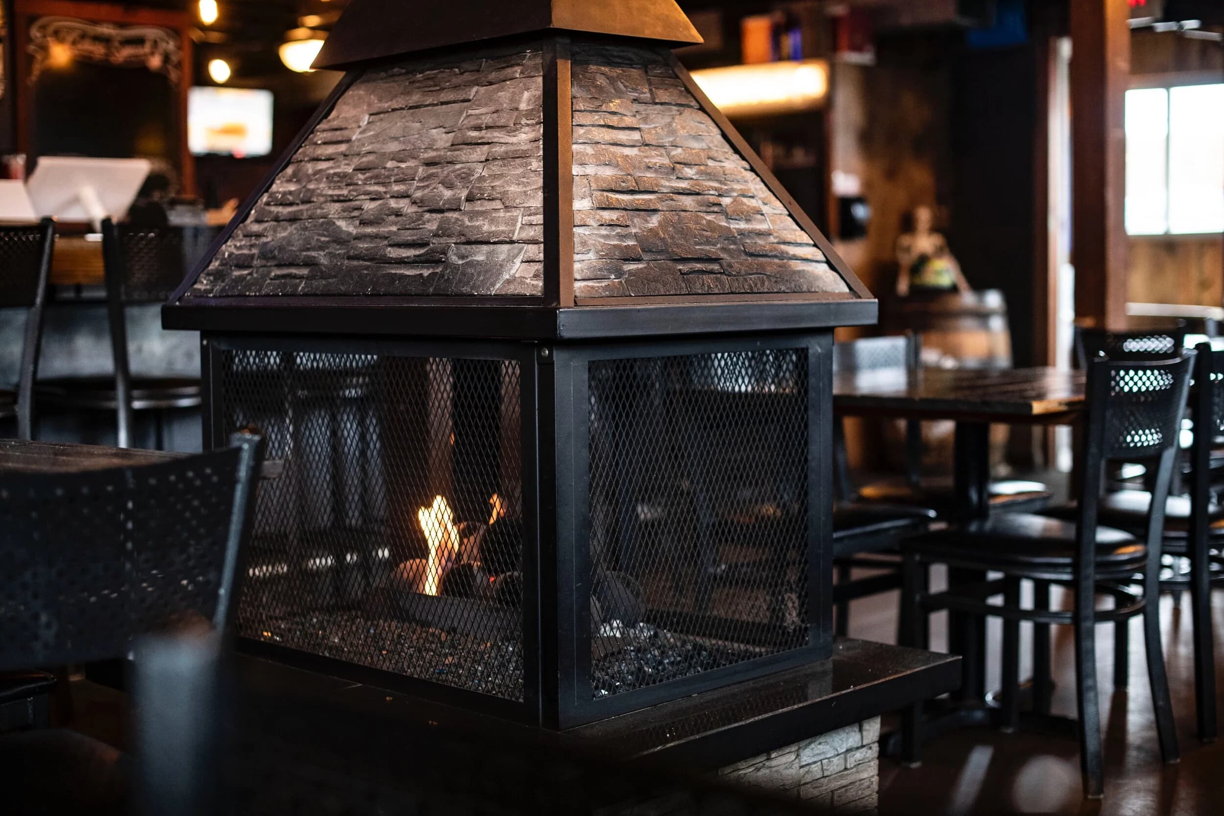 The stone firepit lit among tables on SOHA's covered patio