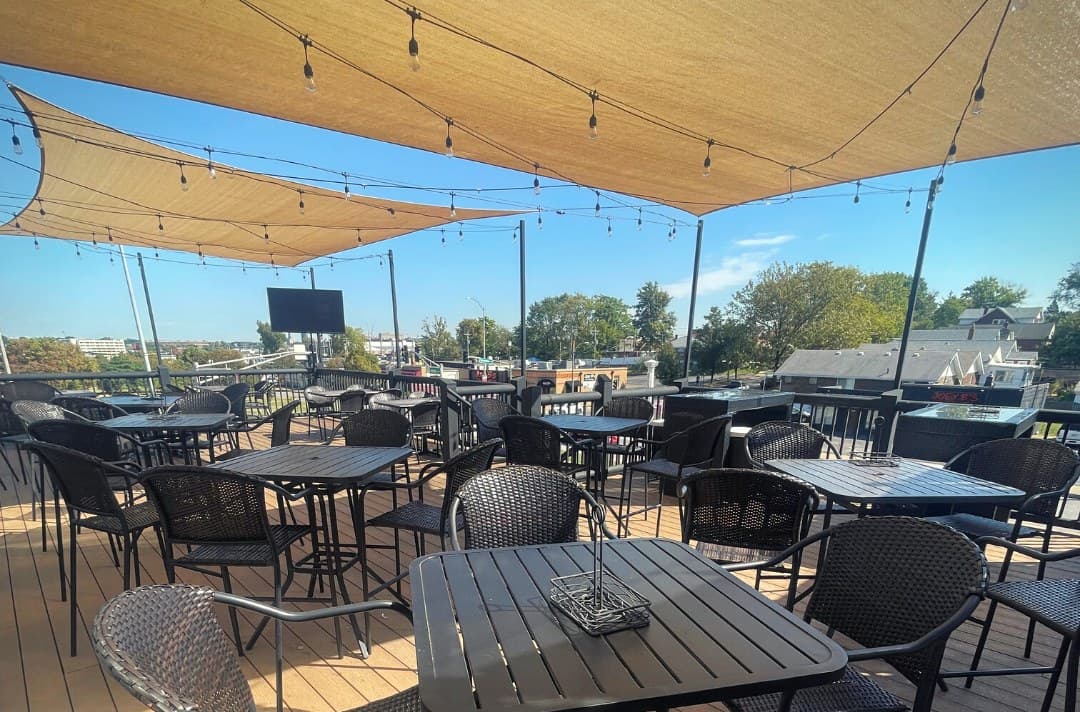 The upstairs patio with tables under shade sails and string lights