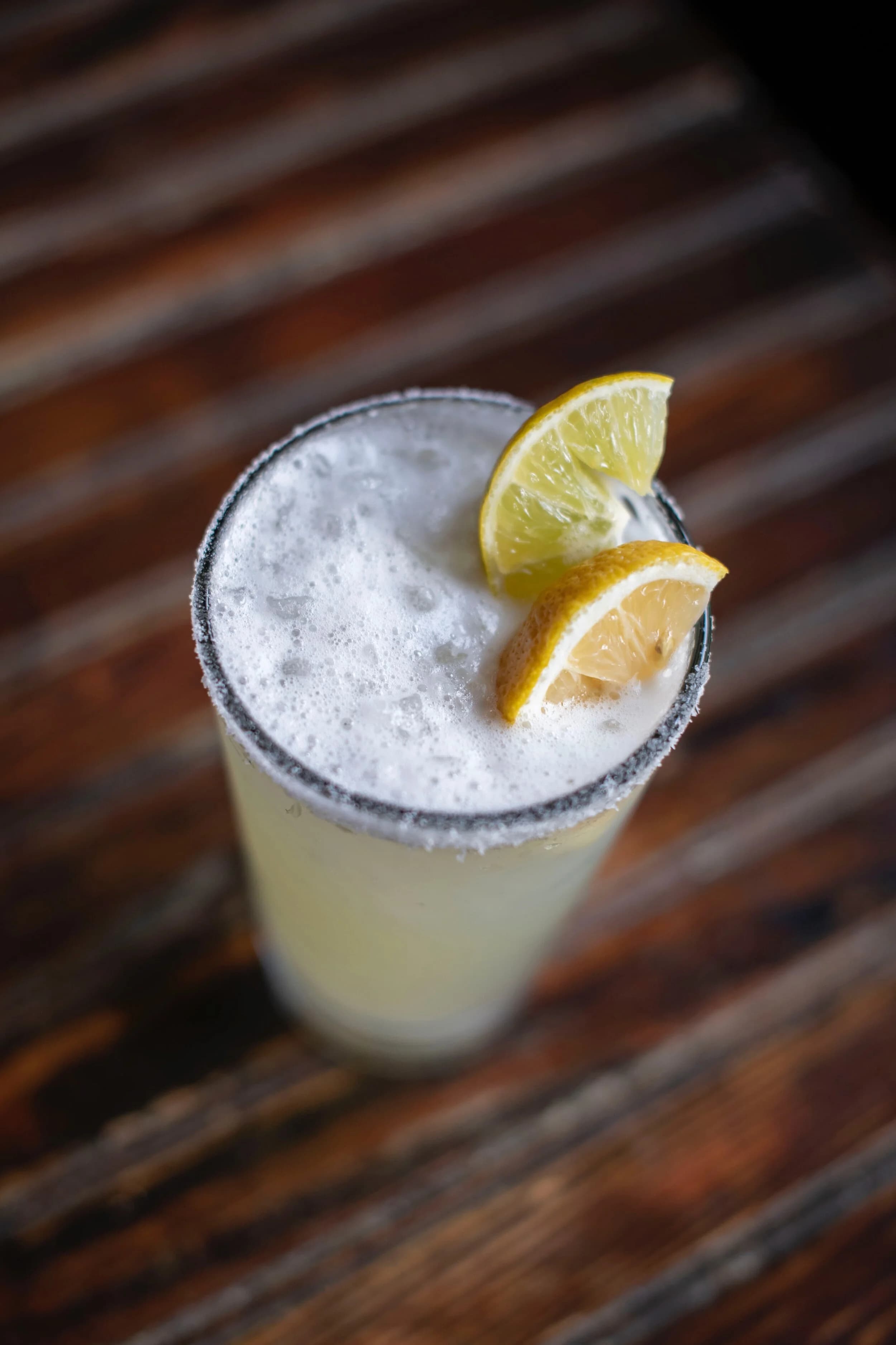 A margarita garnished with orange and lime wedges on the bar